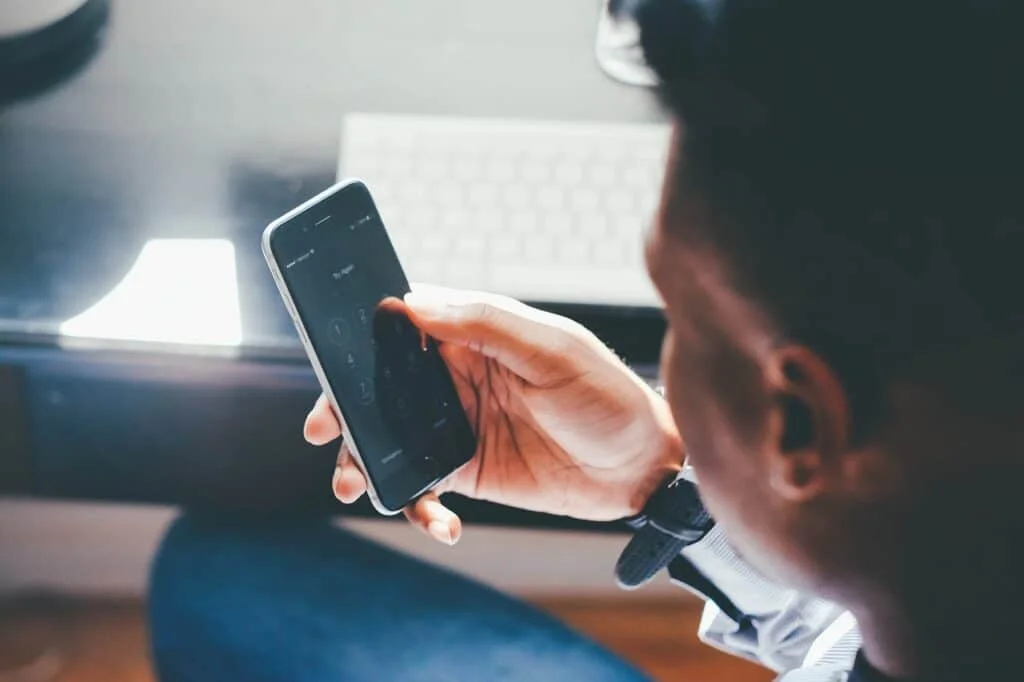 Image of a person holding a smartphone with headphones on, listening to a podcast about epilepsy