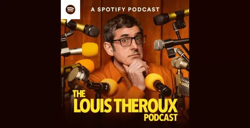 Louis Theroux sitting in a recording studio, speaking into a microphone during a podcast session.
